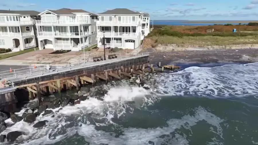 Storm waves breaking against a seawall in front of shoreline homes
